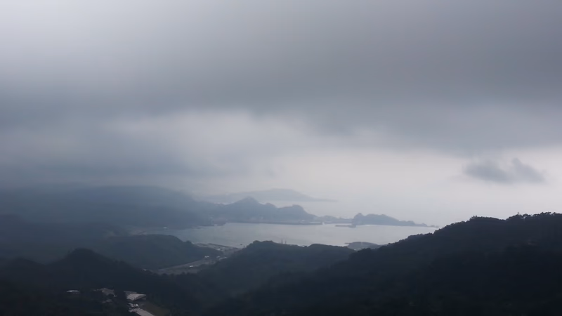 A photo of a coastal landscape with mountains in the background and a body of water in the distance.